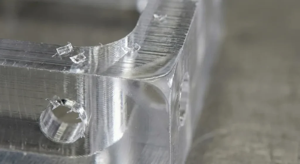 Macro view of milled PMMA surface showing toolpath lines, small chips, and a slight heat smear zone near an edge