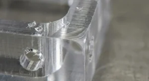 Macro view of milled PMMA surface showing toolpath lines, small chips, and a slight heat smear zone near an edge